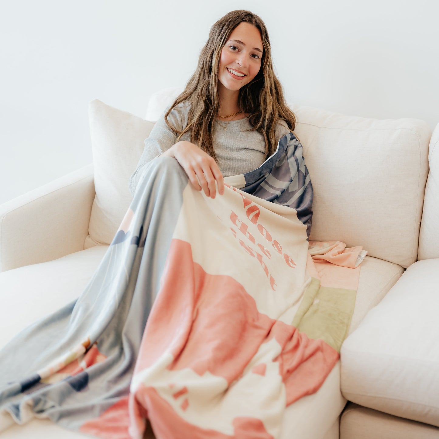 Girl sitting on a couch wrapped in a Christian blanket featuring the CTR Baptism design, celebrating faith and the covenant of baptism.