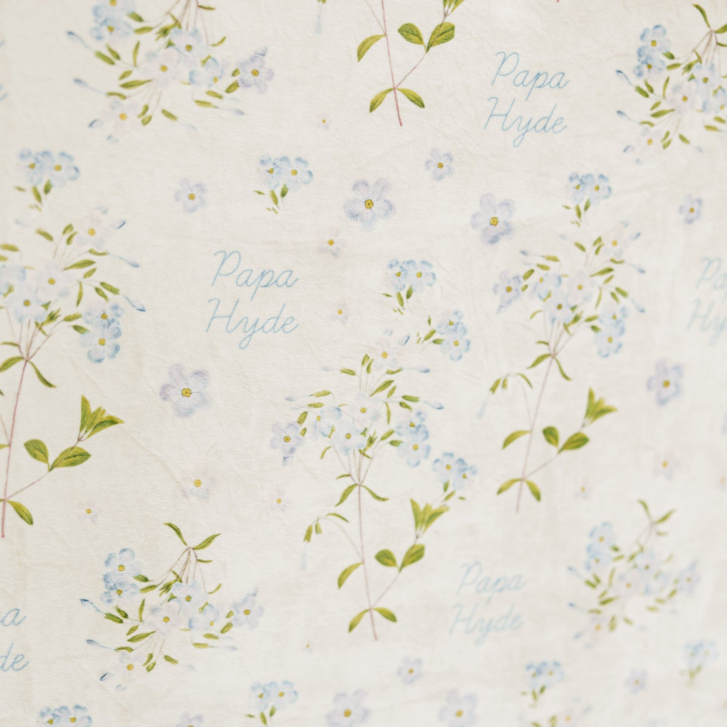 Close-up of a personalized Forget Me Not sympathy blanket featuring delicate blue floral artwork and a custom name woven throughout the design, meaningful memorial blanket created to honor and remember loved ones.