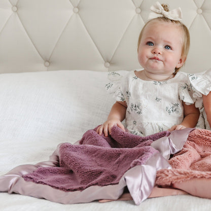 Mini blanket with a velvety surface and a sleek satin border, designed to combine warmth with a sophisticated, silky finish.