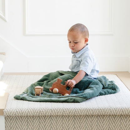 A little boy sits under a Luxury Receiving Hunter Green Colored Lush Saranoni Blanket. The soft blanket is a small blanket and a baby blanket or toddler blanket.