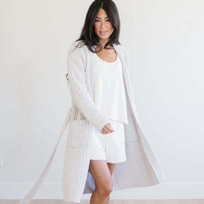 Woman standing at home, wearing a soft, gray waffle knit robe.
