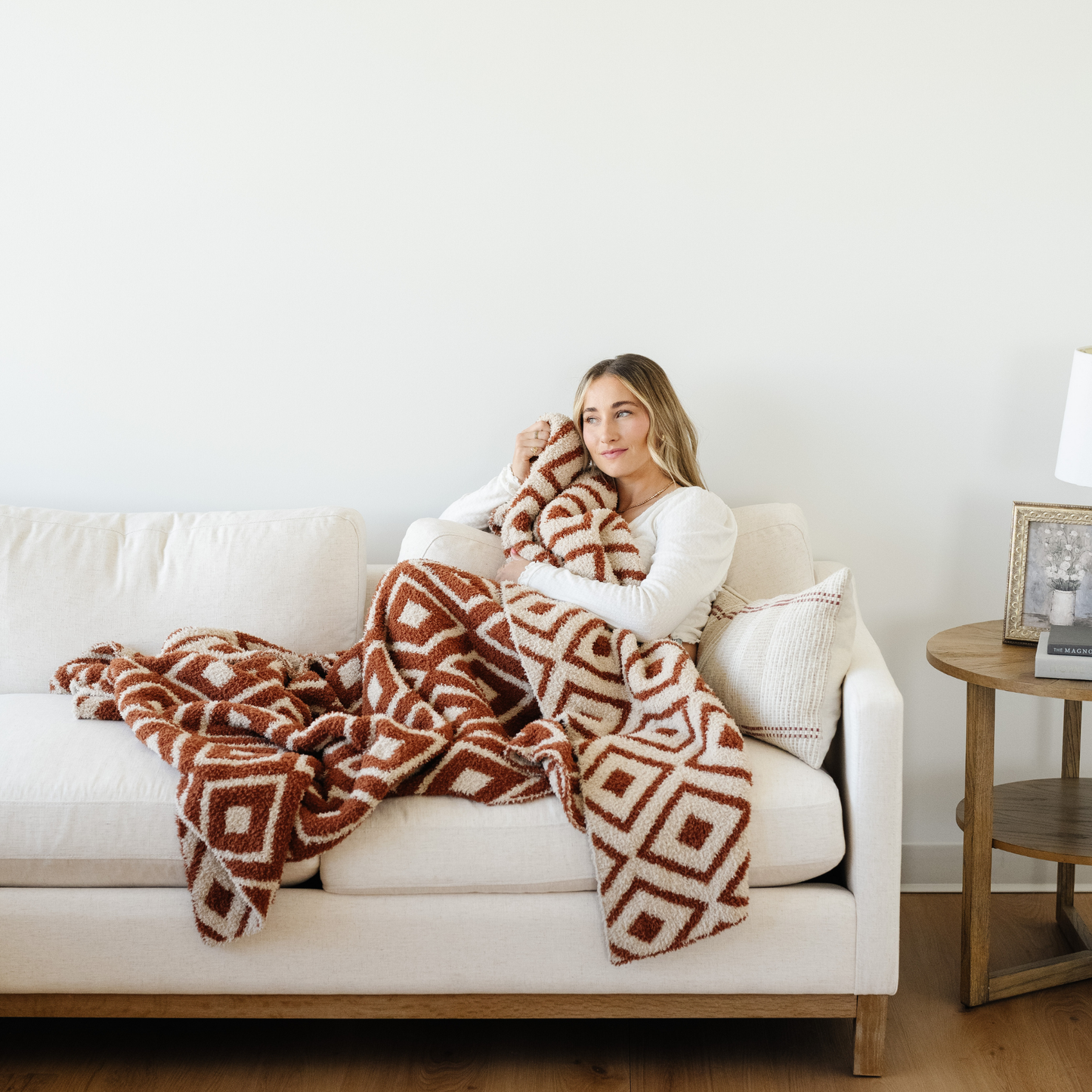 Woman snuggled on couch with a Khmer XL blanket that is double layer bamboni.