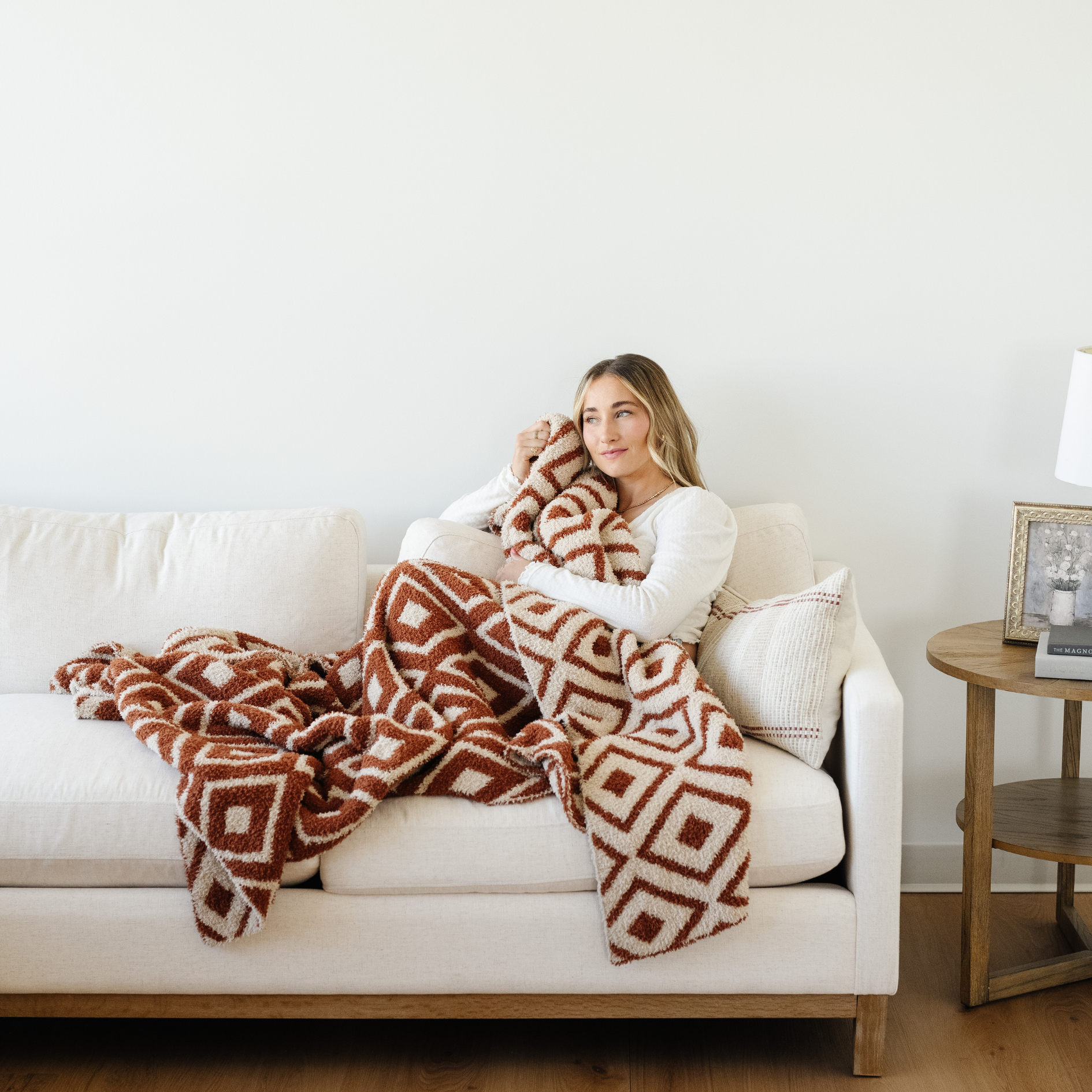 Woman snuggled on couch with a Khmer XL blanket that is double layer bamboni.