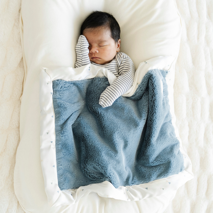 Baby boy snuggled with Satin back Saranoni soft mini baby blanket in Sea Glass print. 