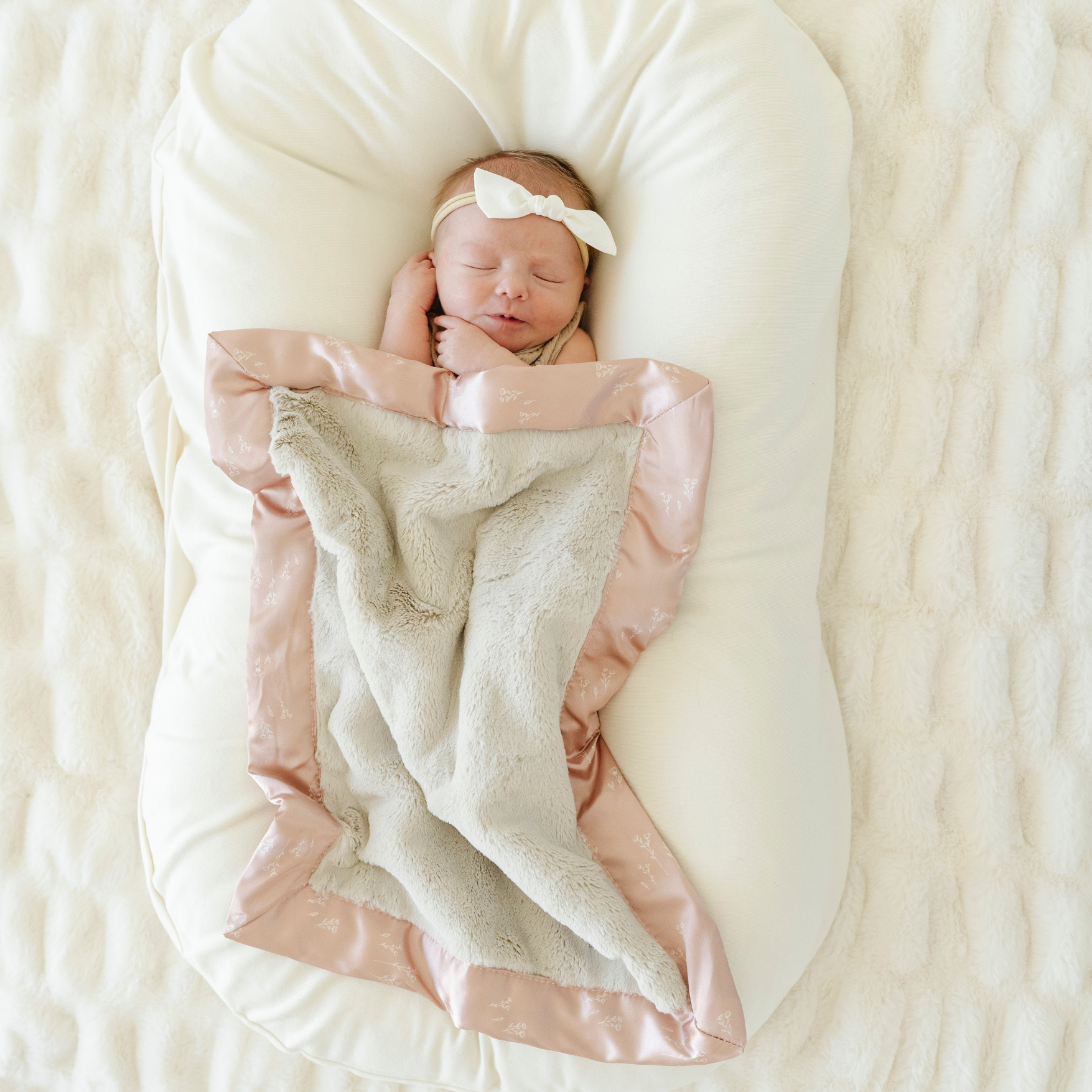 Baby girl snuggled in Satin Border Mini baby blanket in Dainty Floral print. 