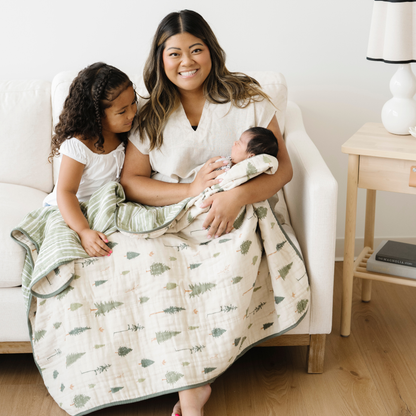 Mom and sister with Baby boy snuggled in Pine Cotton Muslin 4-Layer quilt. 