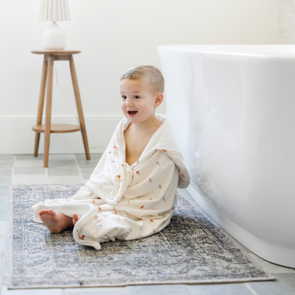 A little boy is wrapped in a Saranoni hooded towel. This luxury hooded towel is perfect for bath time, pool days, and beach outings, being gentle on sensitive skin. Designed as a toddler hooded towel, it provides a cozy, plush feel that keeps little ones warm after water play. Ideal for parents looking for the best soft toddler towel that combines style, durability, and ultimate comfort. This kid's towel has an ice cream print. This is a hooded towel for toddlers and a great bath towel. 