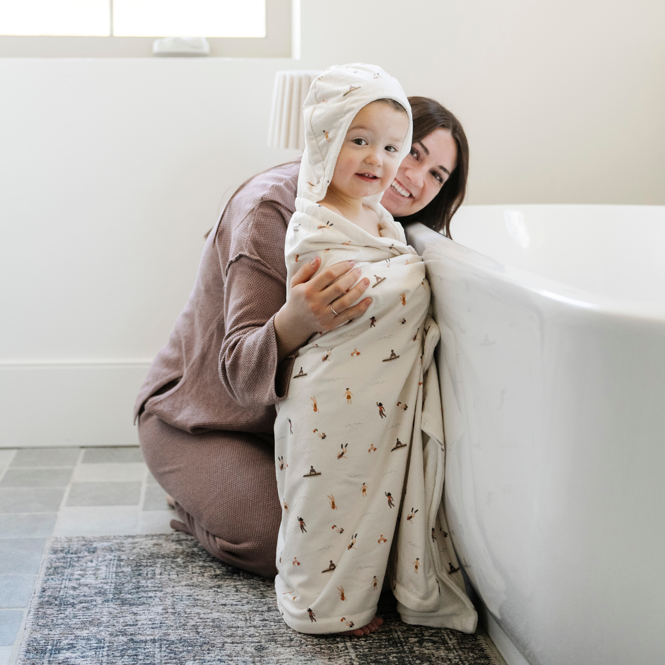 A mother and her toddler who is wrapped in a Saranoni hooded towel, made with soft fabric for maximum absorbency and comfort. This luxury hooded towel is perfect for bath time, pool days, and beach outings, offering quick-drying warmth while being gentle on sensitive skin. Designed as a toddler hooded towel, it provides a cozy, plush feel that keeps little ones warm after water play. Ideal for parents looking for the best soft baby towel that combines style, durability, and comfort. 