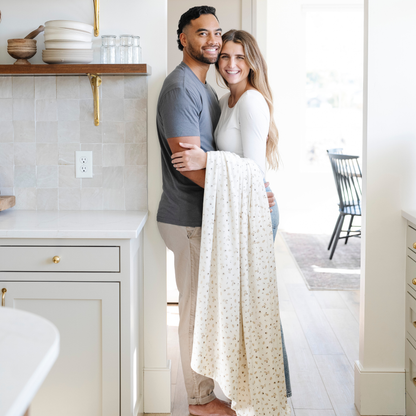 A husband and wife with a floral minky stretch blanket. This soft blanket is a Saranoni blanket and is very durable and stretchy. This cozy blanket is perfect for gifting, lounging, and on the go. 