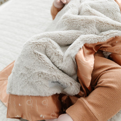 Tan and burnt orange wrap-able receiving blanket.