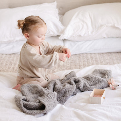 Adorable young girl playing with toys and her favorite gray BAMBONI RECEIVING BLANKETS - Saranoni
