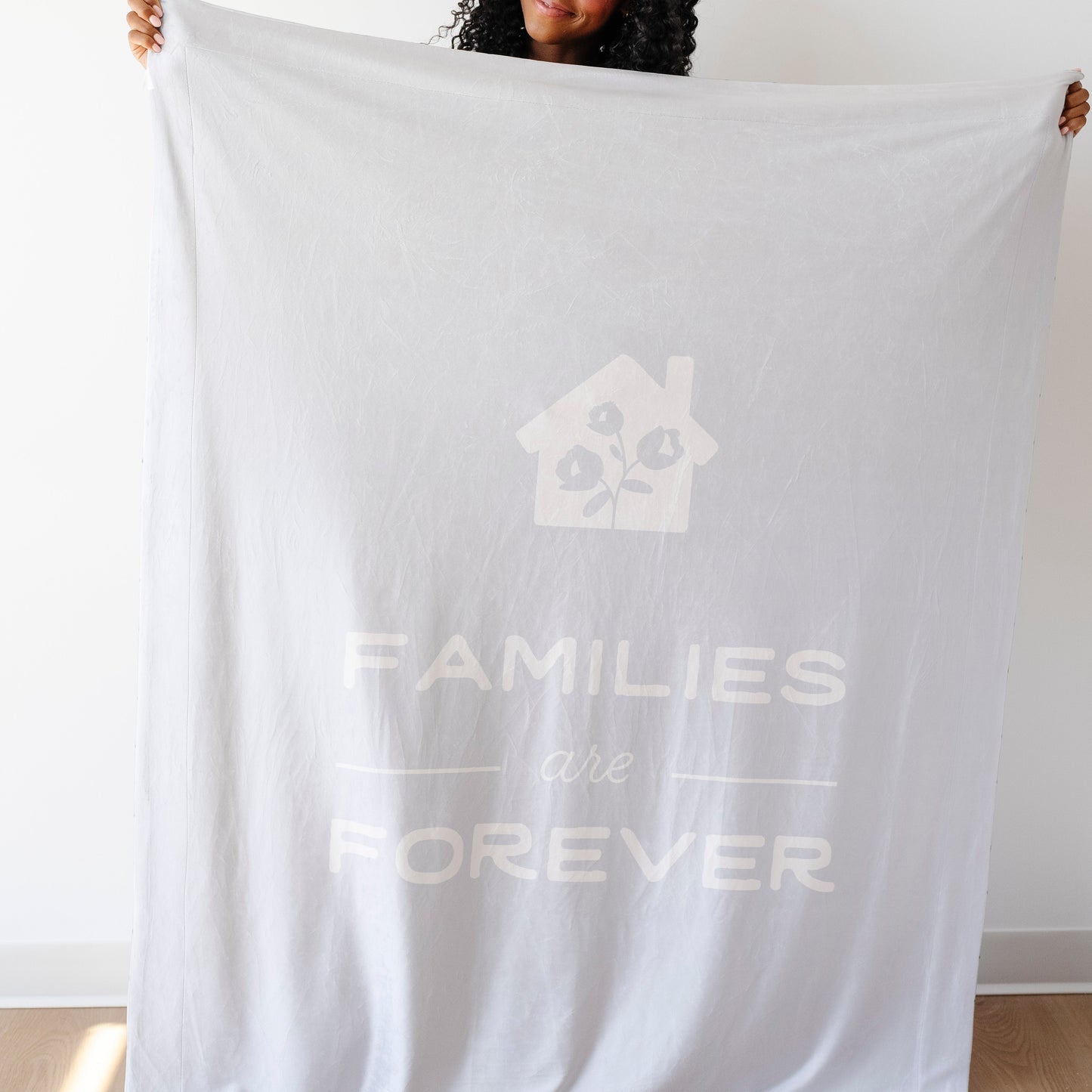 Person holding a light glacier blue LDS blanket featuring the words "Families Are Forever" and a home design, soft faith-inspired throw blanket celebrating eternal families and lasting connections.