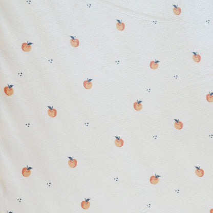 Close-up of Minky Stretch Luxe fabric in a delicate apple pattern. Made from 94% polyester and 6% spandex, this ultra-soft, stretchy fabric is perfect for baby essentials like swaddles, changing pad covers, and crib sheets.