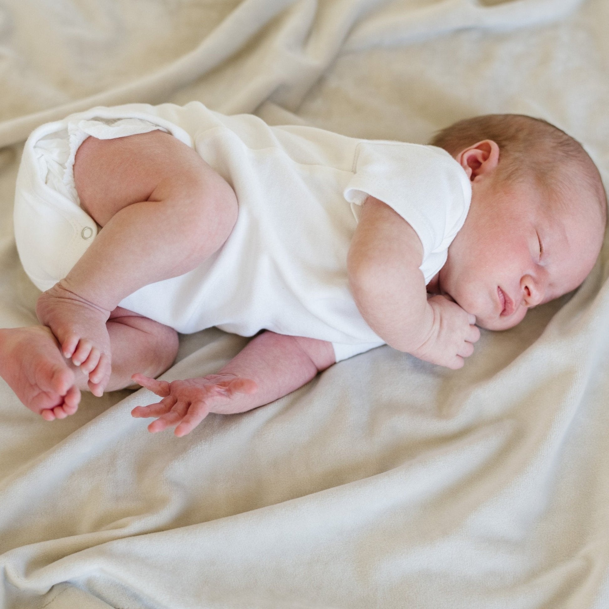 Baby falling asleep on neutral MINKY STRETCH RECEIVING BLANKETS - Saranoni