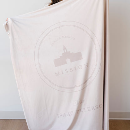Person holding a personalized missionary blanket featuring the Merida Mexico Mission design, missionary name, and custom mission dates.