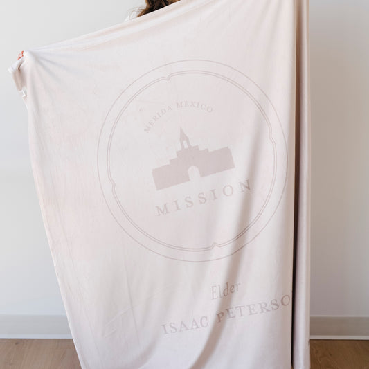 Person holding a personalized missionary blanket featuring the Merida Mexico Mission design, missionary name, and custom mission dates.