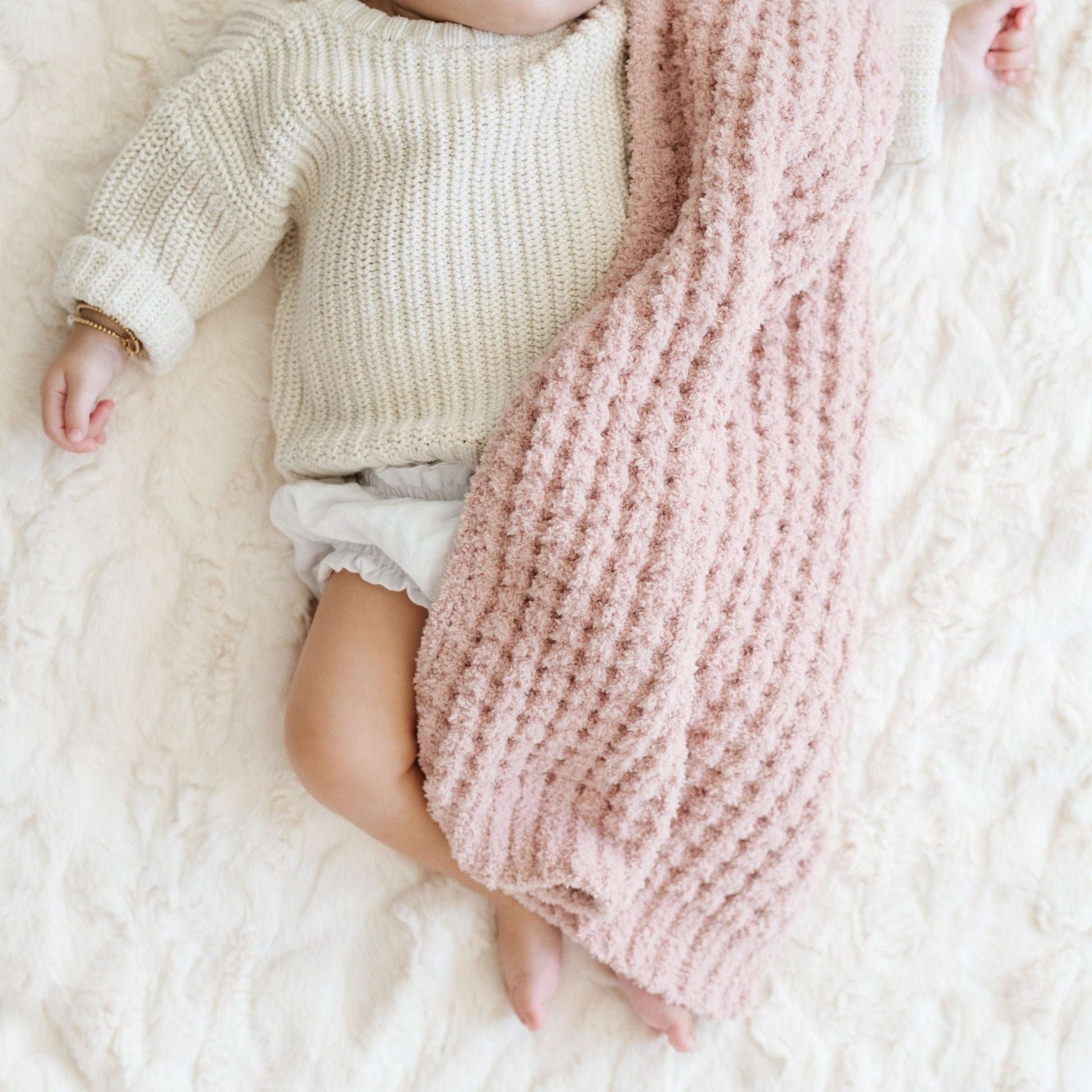 Baby girl sleeping in crib with link waffle knit blanket. 